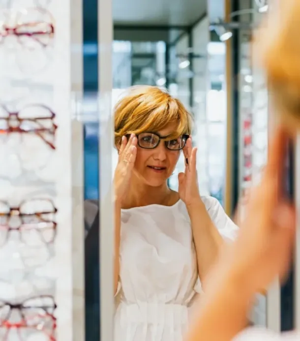 une femme essaie des lunettes dans un magasin d'optique